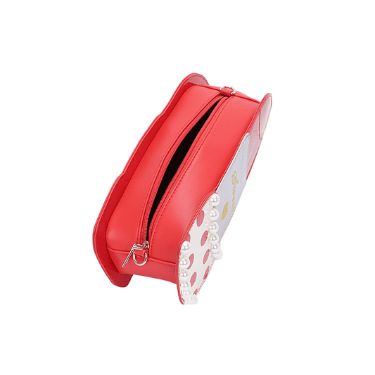 Close-up of red glossy handbag with golden embroidery and polka dot design.